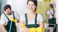 Smiling cleaning lady in uniform and yellow rubber gloves
